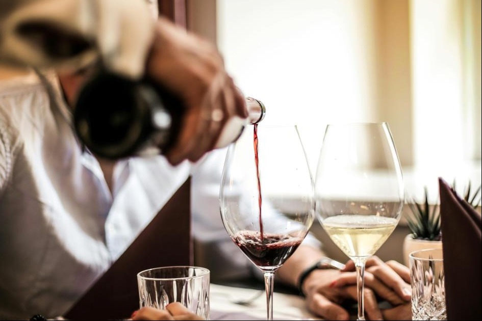Crop man pouring red wine in glass in restaurant