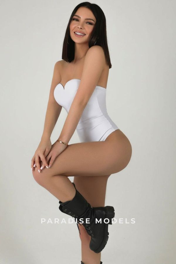 Irina wearing a white one piece, smiling. 