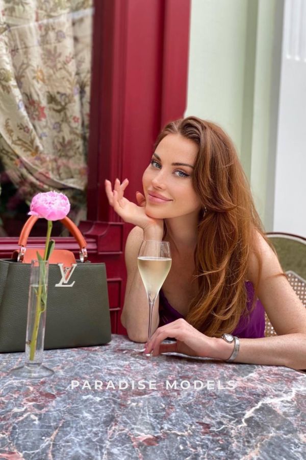 Rachel having a drink of champagne outside next to her LV bag 